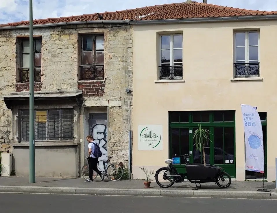 La devanture du Dérailleur à Arcueil, un vélo cargo garé devant la vitrine verte